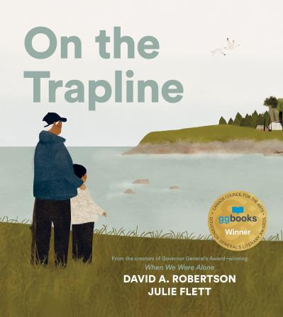 A boy and his Moshom (grandfather) stand in the grass on the shoreline of a river, looking across to Moshom's trapline. 