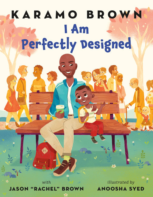 I Am Perfectly Designed by Karamo Brown.  A father and son sit on a park bench smiling at each other.  People of all ages walk on a path in the background. 